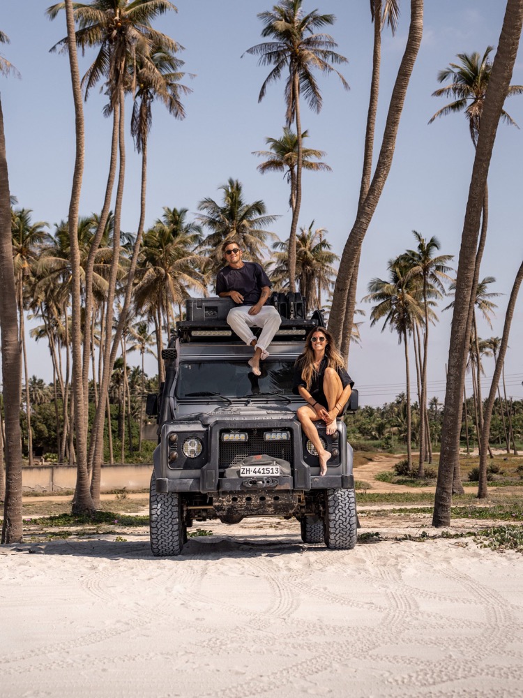 Couple sur le toit d'un 4x4 aménagé sous les palmiers