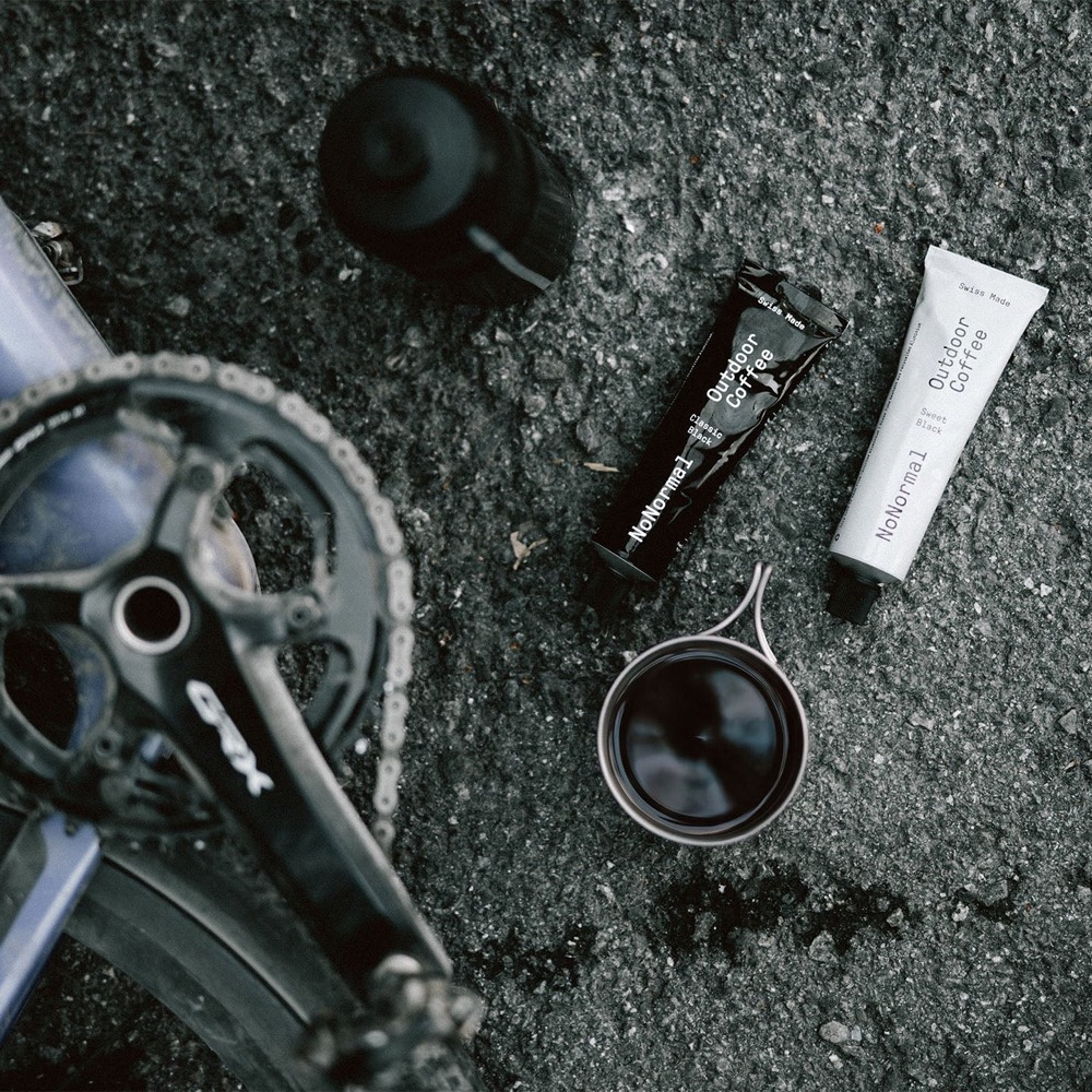 Tubes NoNormal et tasse posés à côté d'un vélo de gravel